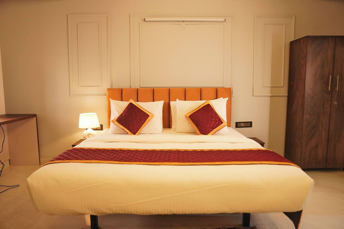 Une chambre d’hôtel avec un grand lit, une armoire en bois et une table de chevet avec une lampe.