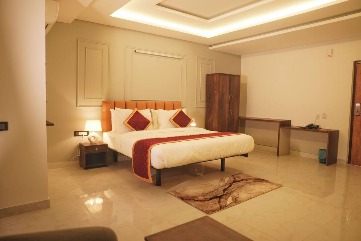 Une chambre d’hôtel moderne équipée d’un grand lit, d’une table de chevet, d’un bureau et d’une armoire.