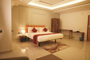 A modern hotel room with a large bed, a nightstand, a desk, and a wardrobe. - Hemagiri Palace (Devanahalli)