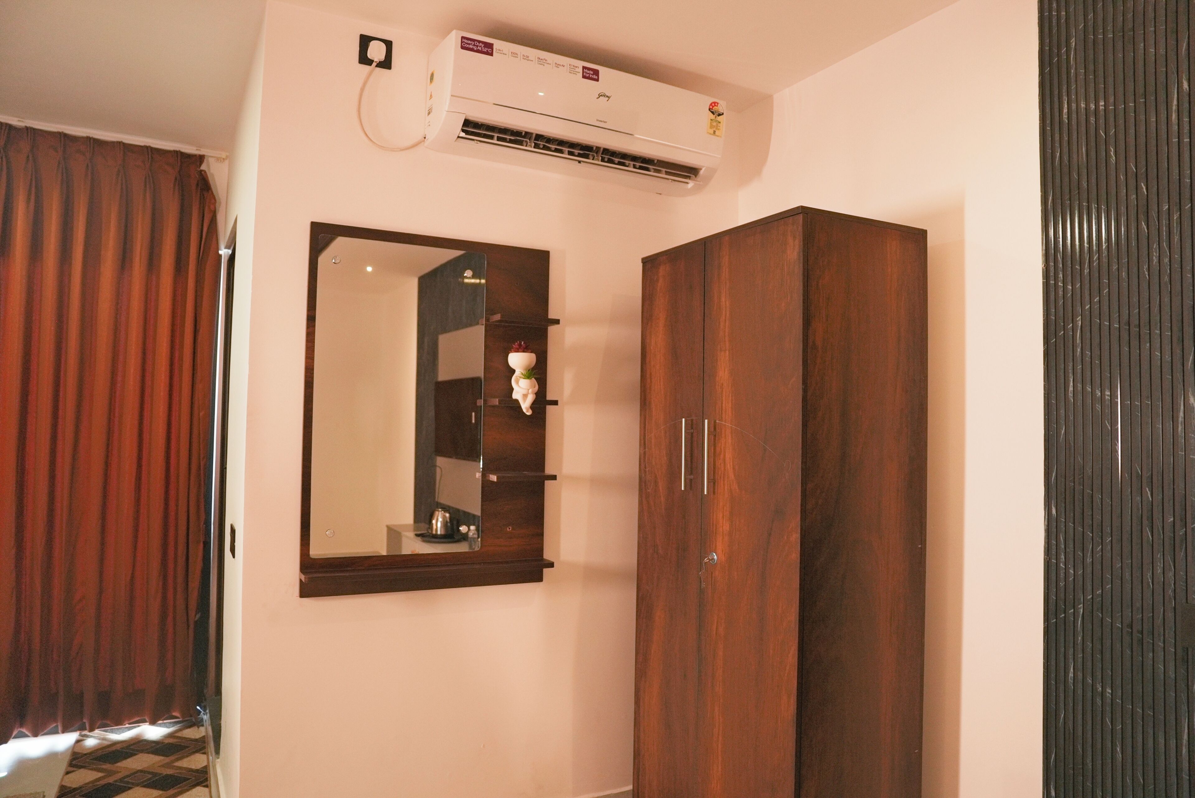 A room with a wooden wardrobe, a mirror, and an air conditioning unit.