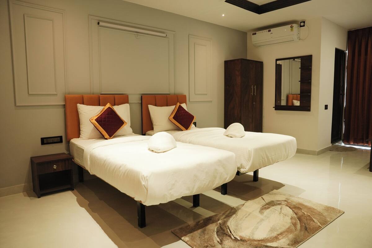 Une chambre d’hôtel avec deux lits, une table de chevet, un miroir et une armoire.
