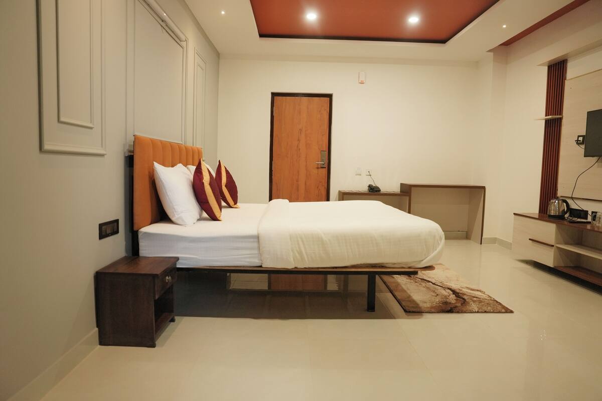 Une chambre à coucher avec un lit, des tables de chevet, une porte en bois, une télévision et un bureau.
