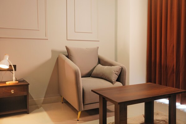 A room with a sofa, a wooden side table with a lamp, a wooden coffee table, and a brown curtain. - Hemagiri Palace (Devanahalli)