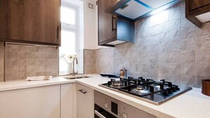 Una cocina moderna con estufa a gas, armarios blancos y ventana con vistas.
