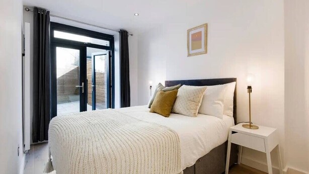 Un dormitorio con cama, mesita de noche y vistas por una ventana.