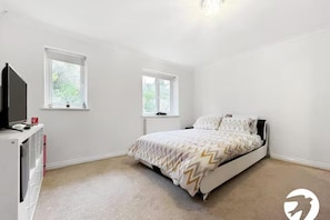 A bedroom with a bed, two windows, a television, and a white wardrobe. - 5 Bed with superfast Wifi for short and long stay (Chatham)
