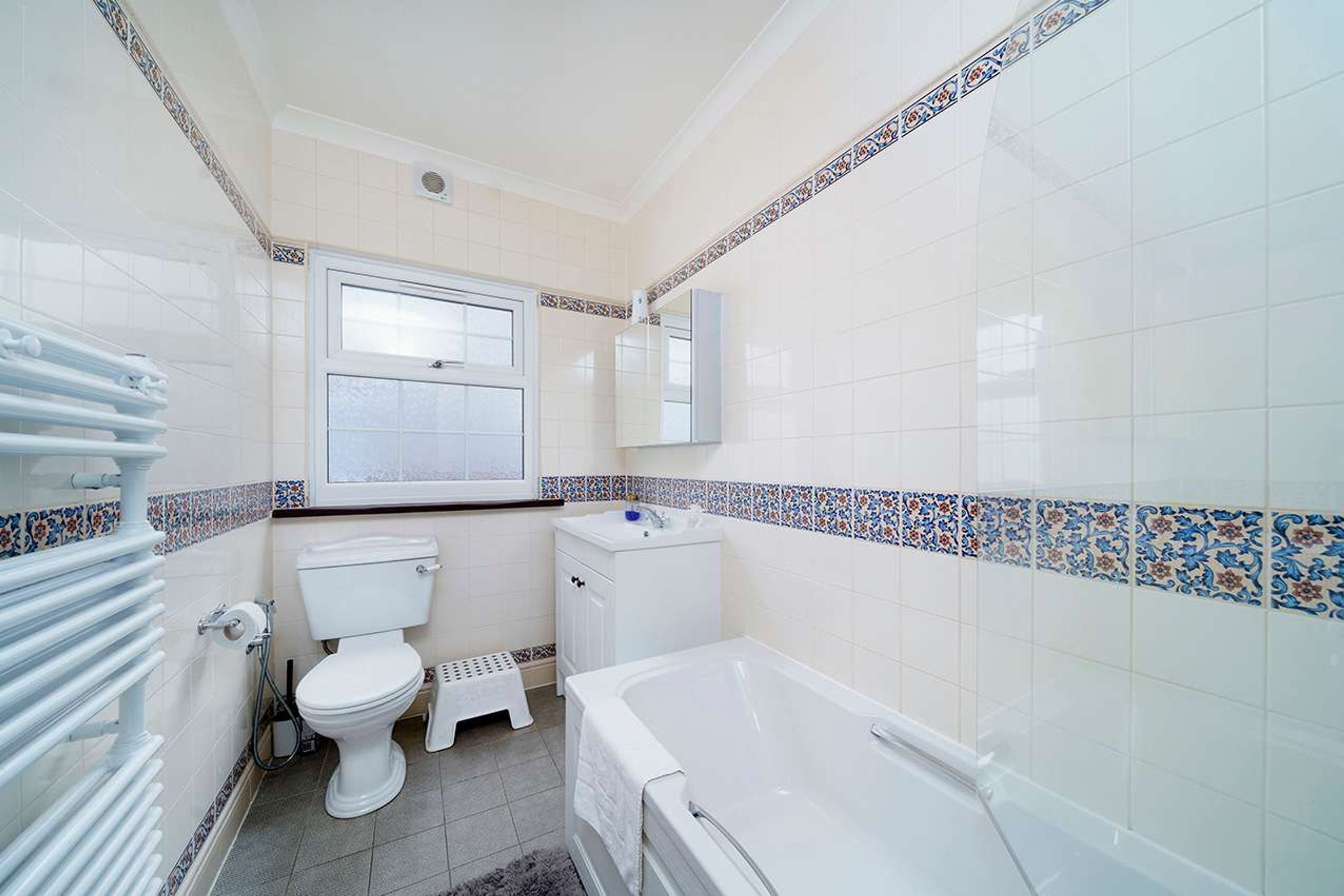 Et badeværelse med toilet, vask og badekar.