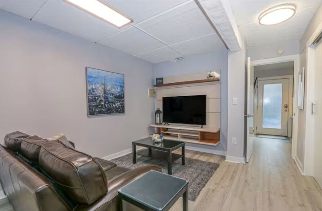 A living room with a brown leather sofa, a flat-screen TV, and a coffee table.