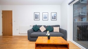 A living room with a grey sofa, a wooden coffee table, and three framed pictures on the wall.
