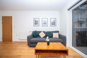 A living room with a grey sofa, a wooden coffee table, and three framed pictures on the wall.