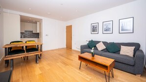 A modern living room with a grey sofa, wooden coffee table, and a dining area with a wooden table and chairs.