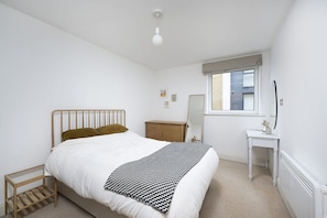 A bedroom with a bed, bedside table, dresser, and a window. - Charming 1 Bedroom Flat in Lambeth (Greater London)