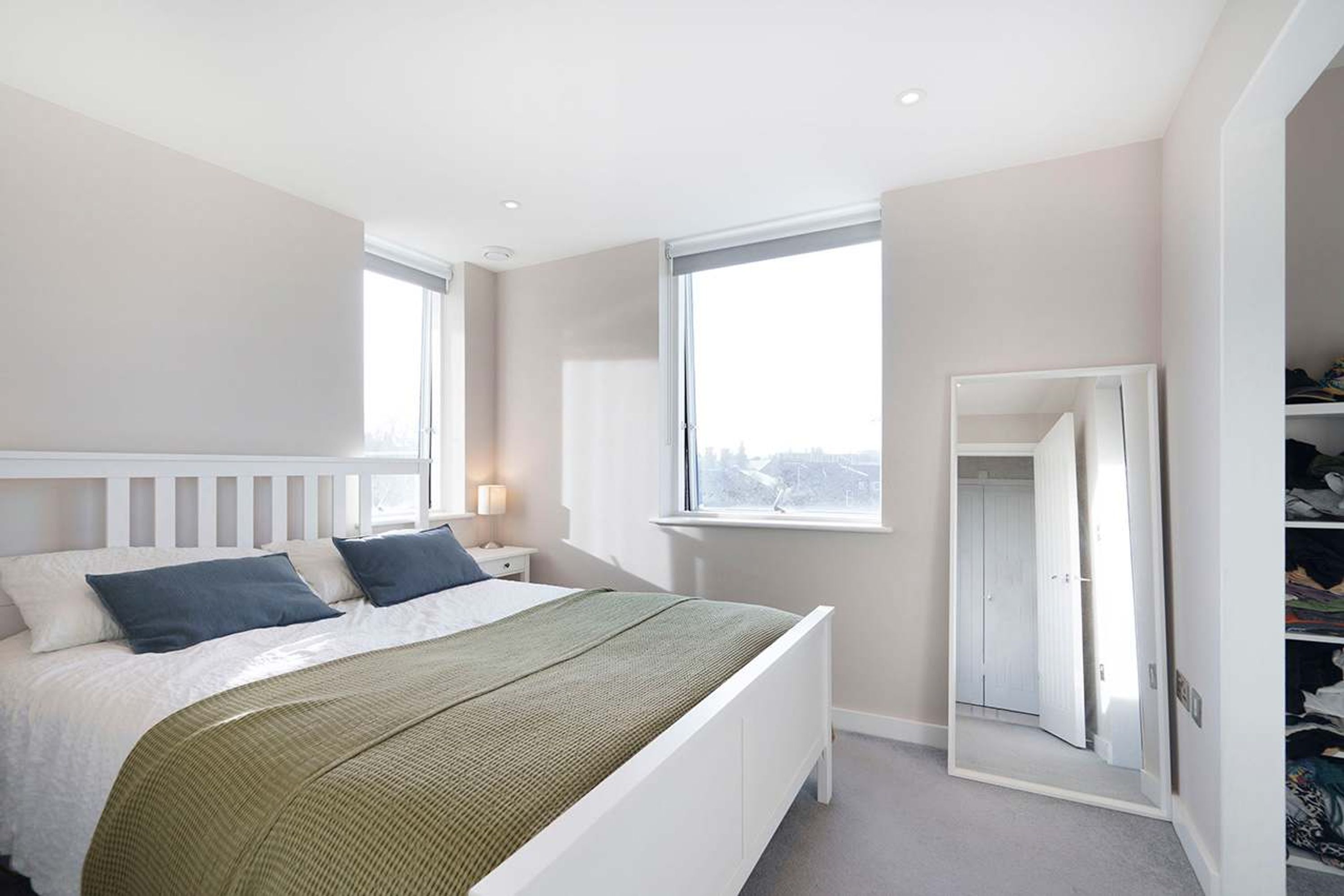 A bedroom with a bed, a nightstand, a window, and a closet.