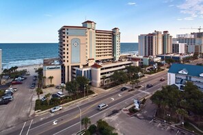A coastal hotel with multiple floors, a parking lot, and a view of the beach and ocean. - Compass Cove 268: Oceanfront (Myrtle Beach)