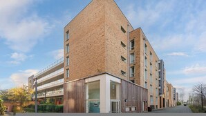 Ein modernes, mehrgeschossiges Gebäude mit markanter Eckarchitektur, großen Fenstern und einer flachen Dachfläche.
