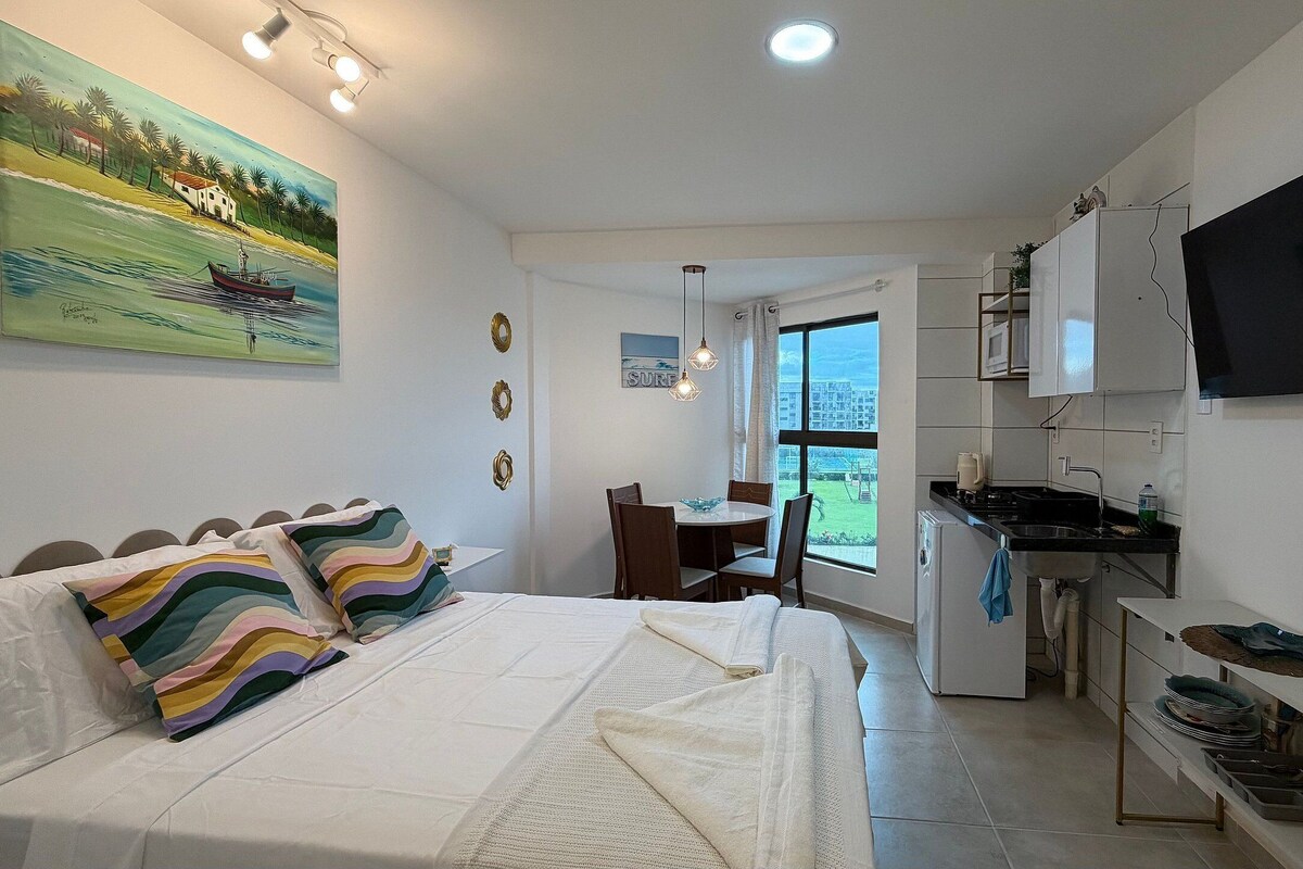 Ein Schlafzimmer mit Bett, Esstisch und Küchenzeile mit Fernseher.