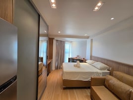 Habitación de hotel con cama, sofá, escritorio y espejo.