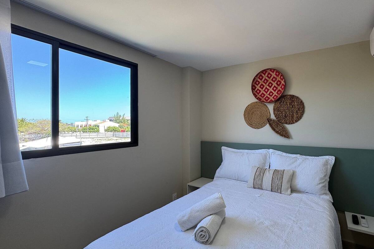 A hotel room with a bed, a window, and a wall-mounted air conditioner.