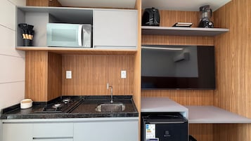 Cocina pequeña con microondas, estufa y televisor de pantalla plana.