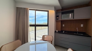 A modern kitchen with a microwave, sink, and dining area with chairs. - Max Carneiros (Tamandaré)
