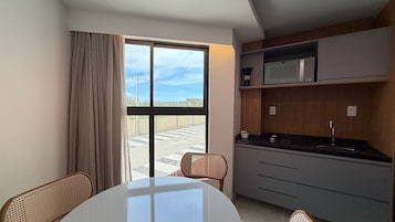 Cocina moderna con microondas, pileta y comedor con sillas.