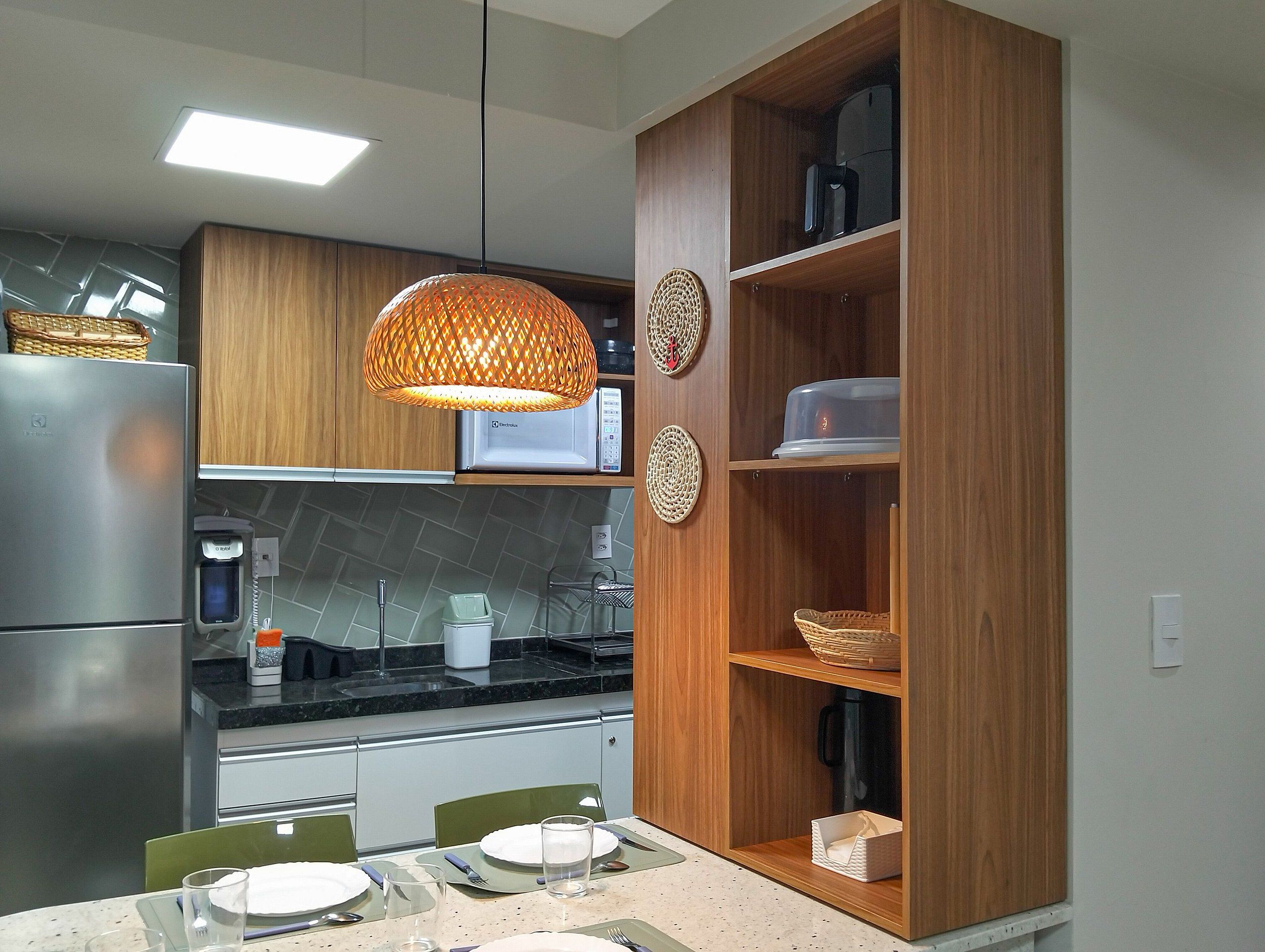 A modern kitchen with a built-in microwave, a stainless steel refrigerator, and a dining area with a table set for two.
