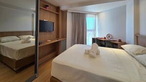 A hotel room with a bed, a TV, a desk, and a window with curtains. - Max Carneiros (Tamandaré)