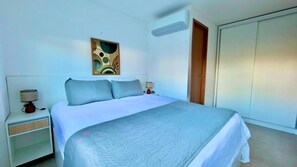 A bedroom with a bed, nightstand, lamp, and a wardrobe. - Max Carneiros (Tamandaré)