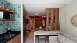 A compact kitchen with a microwave, a sink, and a dining area with a table and chairs. - Max Carneiros (Tamandaré)
