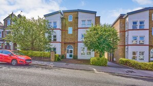 A multi-story residential building with a brick facade, multiple windows, and a green door. - Charming 2-Bedroom Flat in South Croydon (South Croydon)