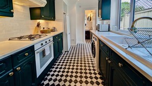 A kitchen with dark green cabinets, a white stove, and a black and white checkered floor.