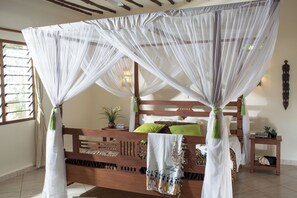 Una cama con dosel, cabecera de madera y almohadas verdes.