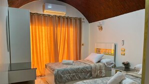 A hotel room with two beds, a wardrobe, a small table, and a mirror. - Wanas kato  (Aswan)
