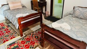 A room with two wooden beds, a desk, a chair, and a shower area. - Wanas kato  (Aswan)