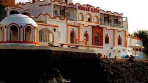 A building with a white facade and orange trim, featuring arched windows and a dome structure. - Wanas kato  (Aswan)
