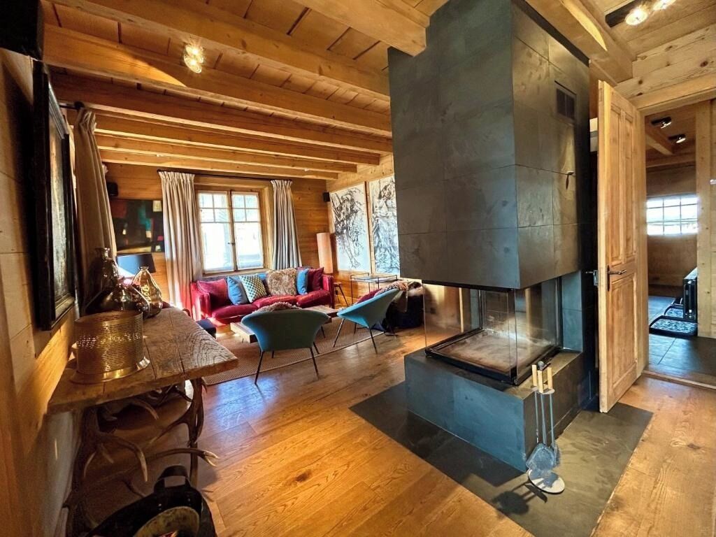Ein gemütlicher Wohnbereich mit Kamin, Holzbalkendecke und einem roten Sofa.