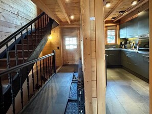 Ein Holzinnenraum mit einer Treppe, einer Küchenzeile und einer Tür zu einem weiteren Raum.