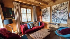 A cozy room with a red sofa, blue chairs, a wooden coffee table, and artwork on the walls. - -La Rosière- Premium Chalet, in the center of Villars-sur-Ollon (Villars-sur-Ollon)