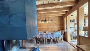 A wooden interior with a dining area, a fireplace, and a view through a glass door. - -La Rosière- Premium Chalet, in the center of Villars-sur-Ollon (Villars-sur-Ollon)