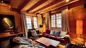 A cozy room with a wooden ceiling, a red sofa, a blue armchair, a coffee table, and a television on the left wall. - -La Rosière- Premium Chalet, in the center of Villars-sur-Ollon (Villars-sur-Ollon)