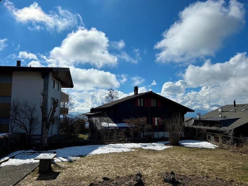 Ein Wohngebiet mit einem Haus, einer Bank und einer schneebedeckten Rasenfläche.