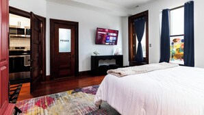 Hotelkamer met een bed, een aan de muur bevestigde televisie, een open haard en uitzicht door een raam.