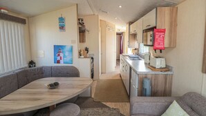 Un intérieur de camping-car compact comprenant un coin repas, une kitchenette et des sièges.