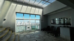A spacious balcony with a city view, a seating area with chairs, and a large window. - HOTEL PERDIZES - Flat Executivo - 1402 (São Paulo)