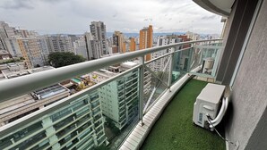 A high-rise building with multiple balconies, a glass railing, and a view of the cityscape. - HOTEL PERDIZES - Flat Executivo - 1402 (São Paulo)
