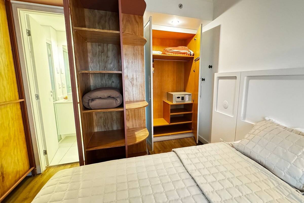 Une chambre à coucher comprenant un lit, une armoire et un four à micro-ondes encastré.