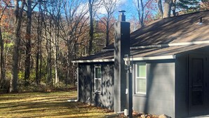 Une maison de plain-pied à l’extérieur sombre, avec une cheminée et une petite fenêtre.