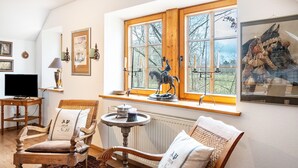 Un salón acogedor con un ventanal grande, muebles de madera, un televisor y objetos decorativos.