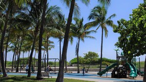 A park with palm trees, a playground, and a blue pathway. - The Netherland 2A (Miami Beach)