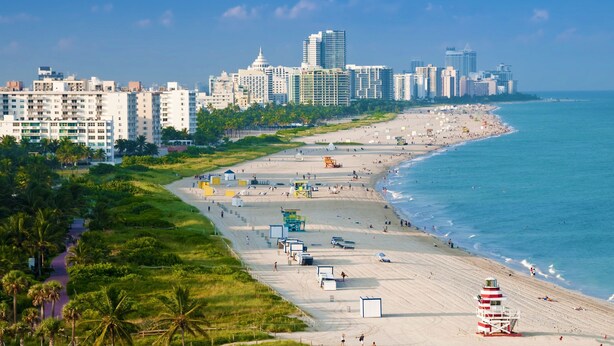 A beach with a city skyline in the background, a sandy beach, and a lifeguard tower. - The Netherland 2A (Miami Beach)